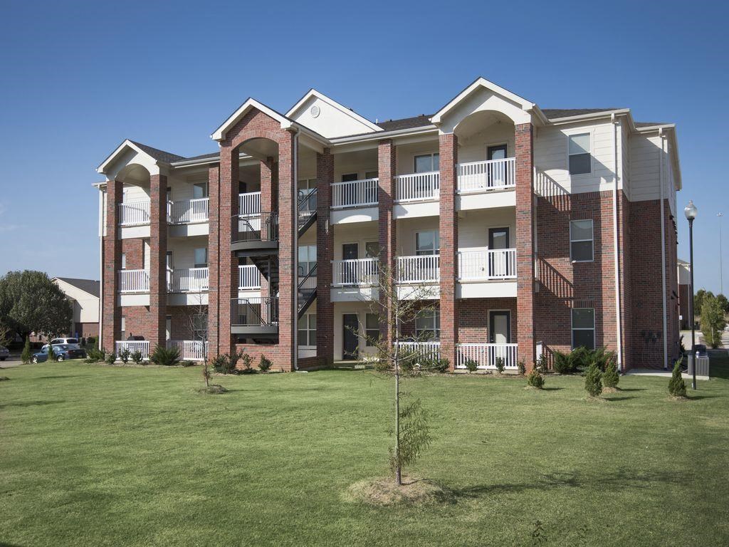 an exterior view of an apartment building with green grass