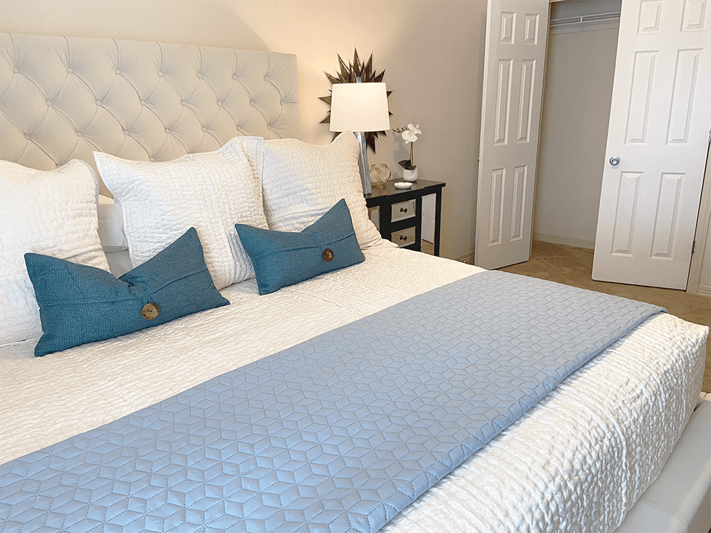 a white bed with blue pillows in a bedroom