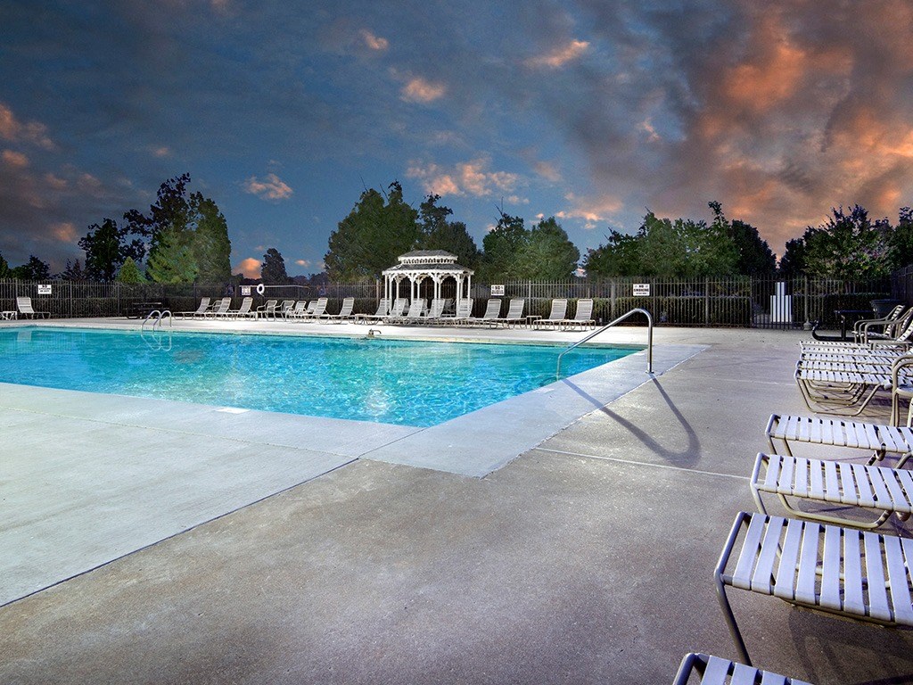a swimming pool with white chairs and a cloudy sky