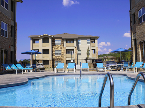 a swimming pool with blue chairs and a building in the background