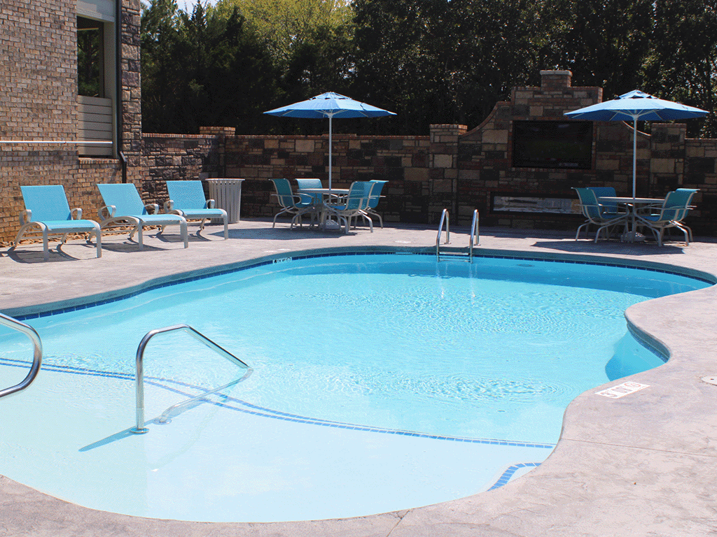 a large swimming pool with chairs and umbrellas on the side of a building