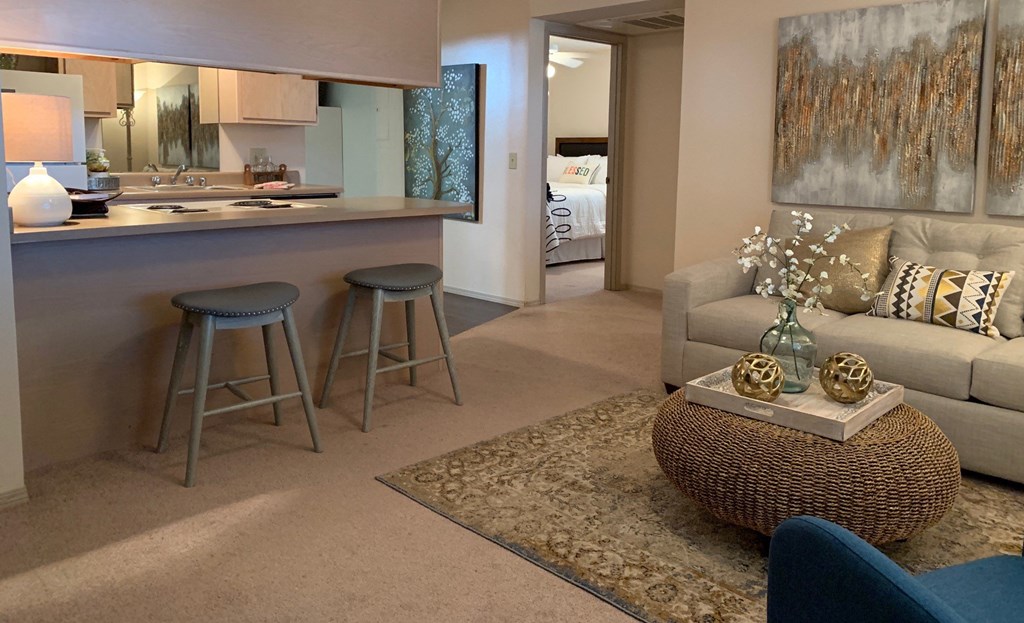 A living room with a couch, a bar, and a painting on the wall.