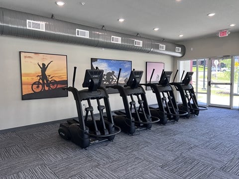 A gym with treadmills and a painting of a person on a bike on the wall.