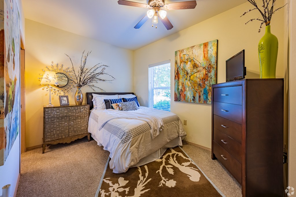 a bedroom with a bed and a dresser and a ceiling fan