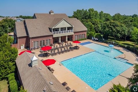 a large swimming pool with umbrellas and a building with a resort style pool