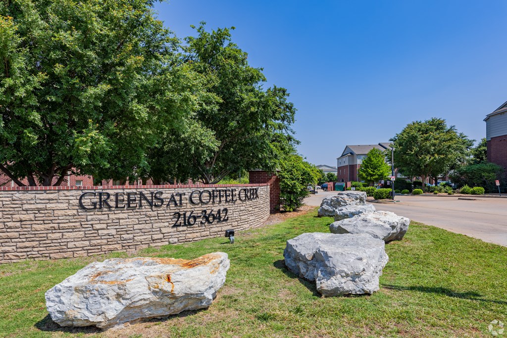 four rocks sitting in front of a brick wall with the greens sign