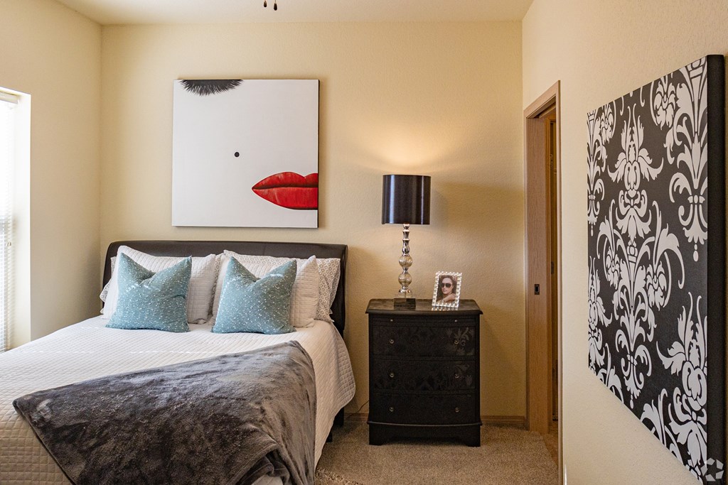 A bedroom with a large bed and a painting of a red mouth above it.
