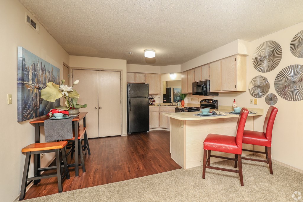 a living room with a kitchen and a bar with red chairs