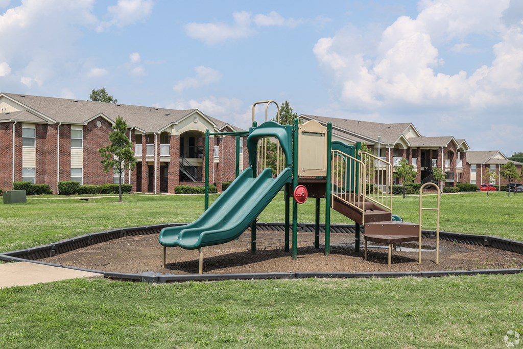 a playground with a slide in front of an apartment complex