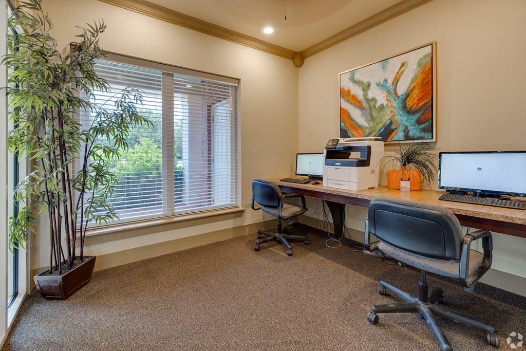 two computers sitting on a desk in a room with a window