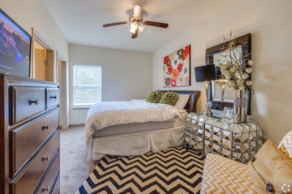 a bedroom with a bed and a dresser and a ceiling fan