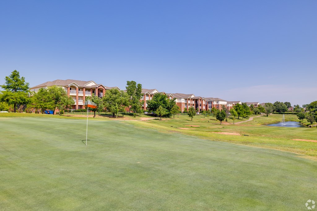 a golf course with an apartment building in the background