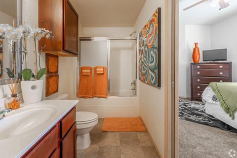 a bathroom with a shower toilet and sink and a bed