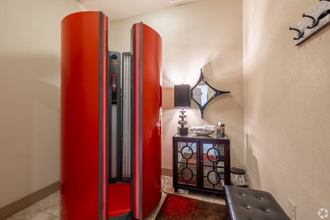 a red refrigerator in the corner of a room with a table and a chair