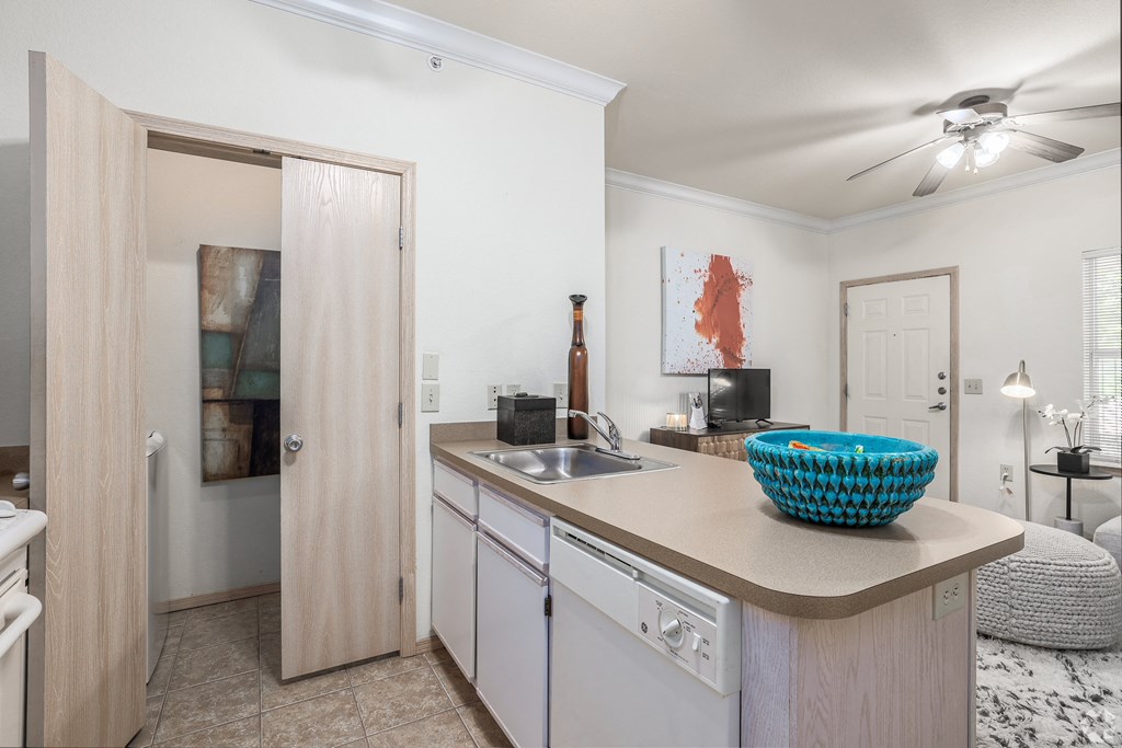 a kitchen with an island and a sink and a door to a living room