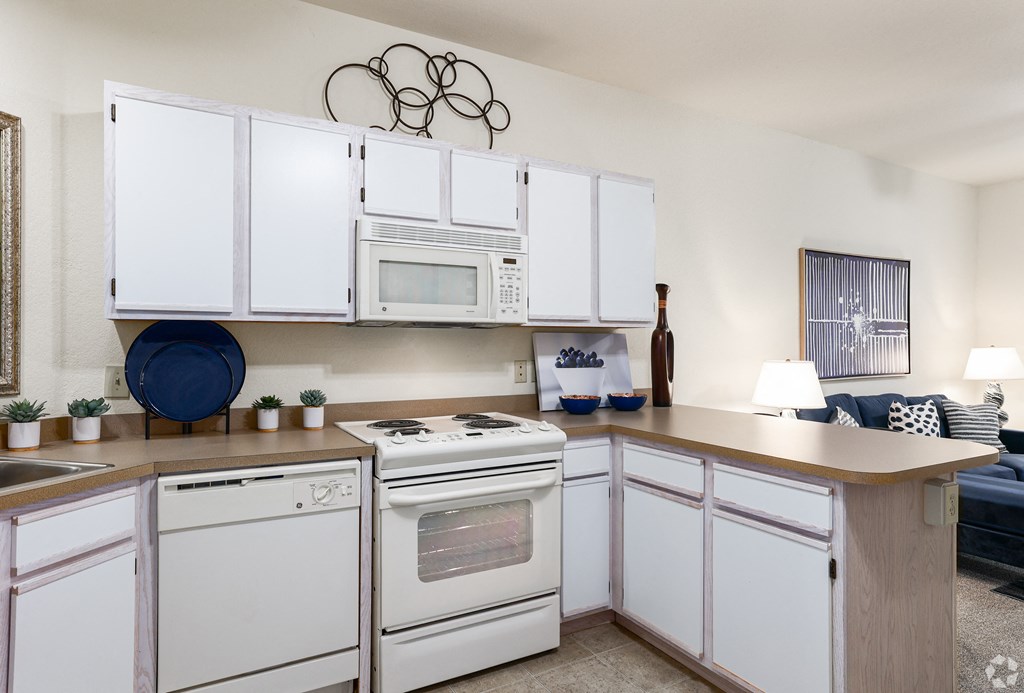 a kitchen with white appliances and white cabinets and a counter top