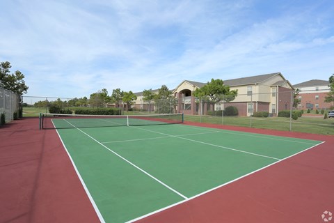 a tennis court with apartments in the background