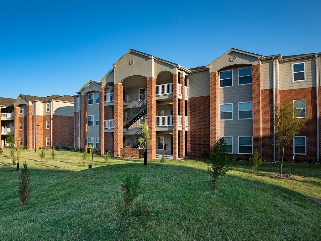 an exterior view of an apartment building with green grass