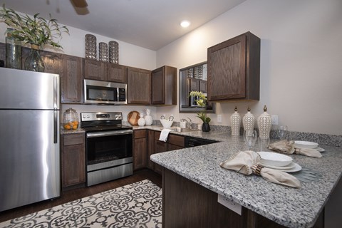 A kitchen with a refrigerator, microwave, oven, and a counter with plates and napkins on it.