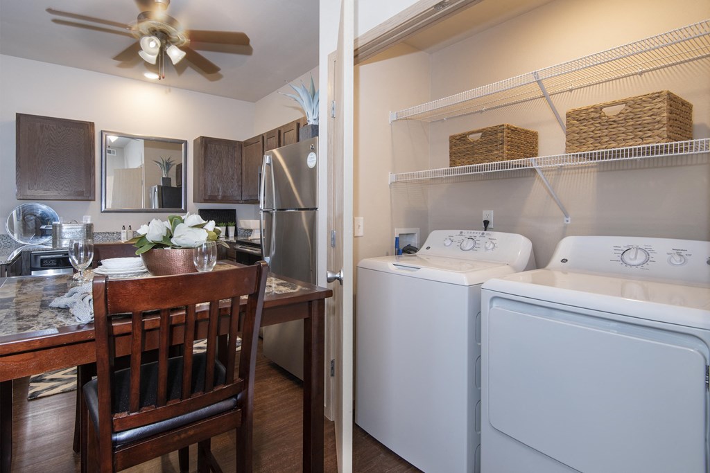 A kitchen with a table and chairs and a laundry room with a washer and dryer.