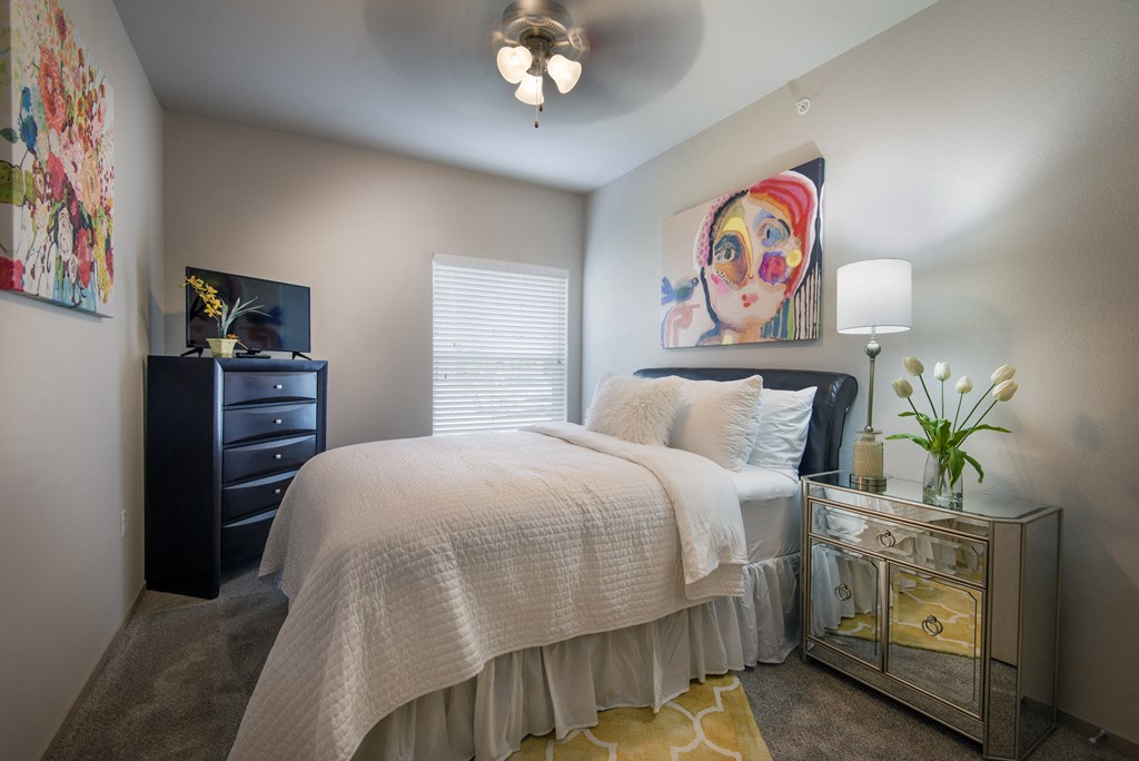 A bedroom with a bed, dresser, and a painting on the wall.
