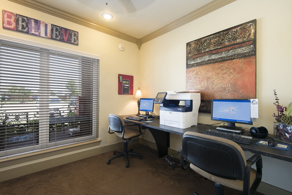 a home office with two computers and a printer on a desk