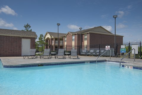 A swimming pool in front of a building with a fence around it.