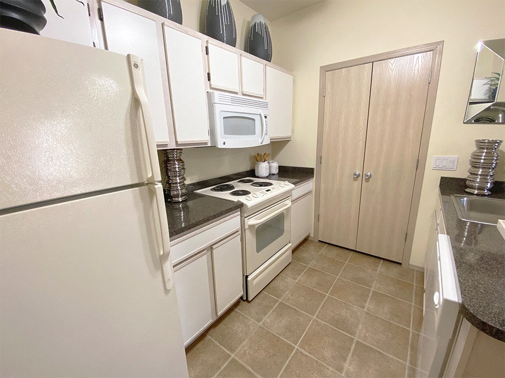 a kitchen with white cabinets and appliances and a refrigerator