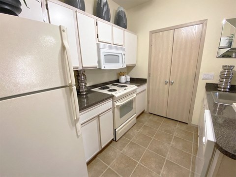a kitchen with white cabinets and appliances and a refrigerator