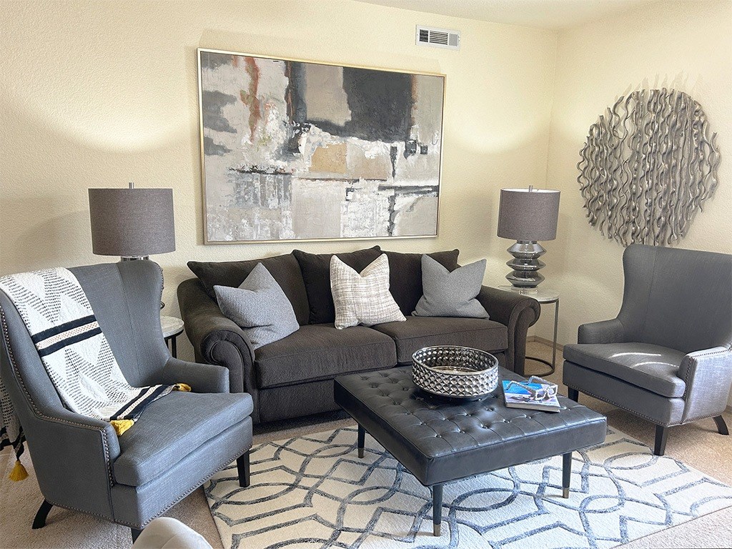 a living room with gray furniture and a painting on the wall