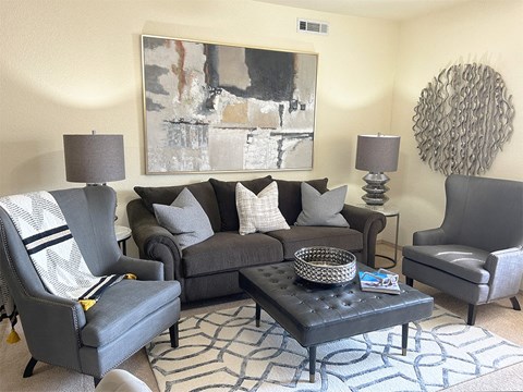 a living room with gray furniture and a painting on the wall