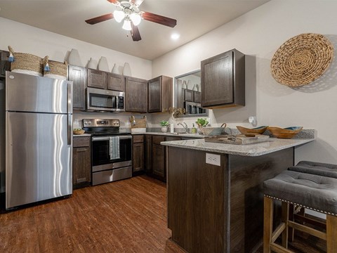 A kitchen with a refrigerator, oven, microwave, and countertop.