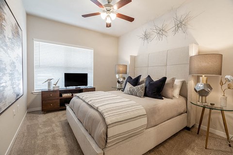 A bedroom with a large bed and a ceiling fan.