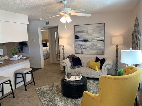 A living room with a yellow chair and a white couch.