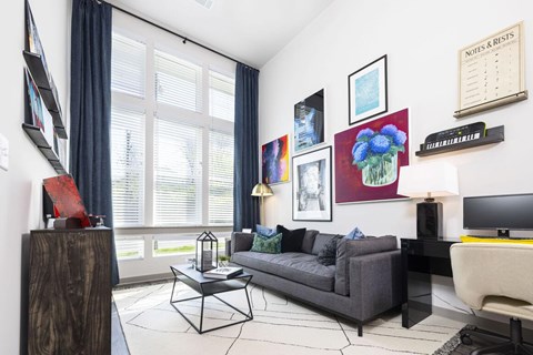 A living room with a grey couch, a coffee table, and a painting on the wall.