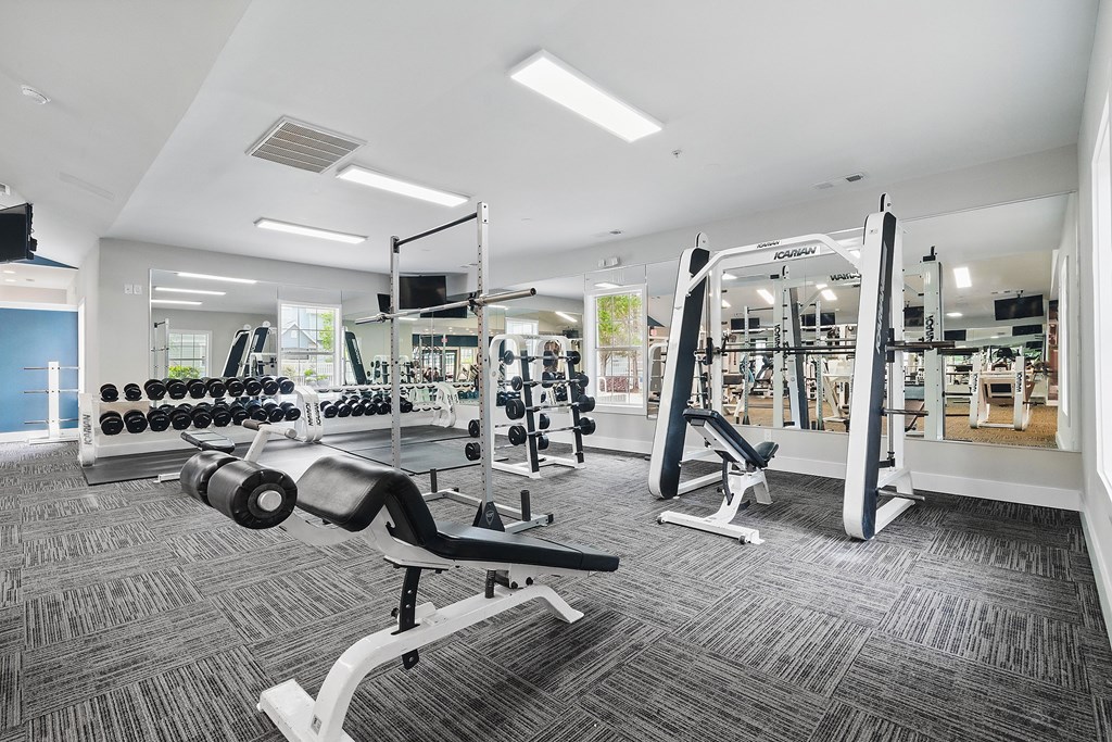 A gym with a variety of equipment including dumbbells, weight machines, and a bench press.