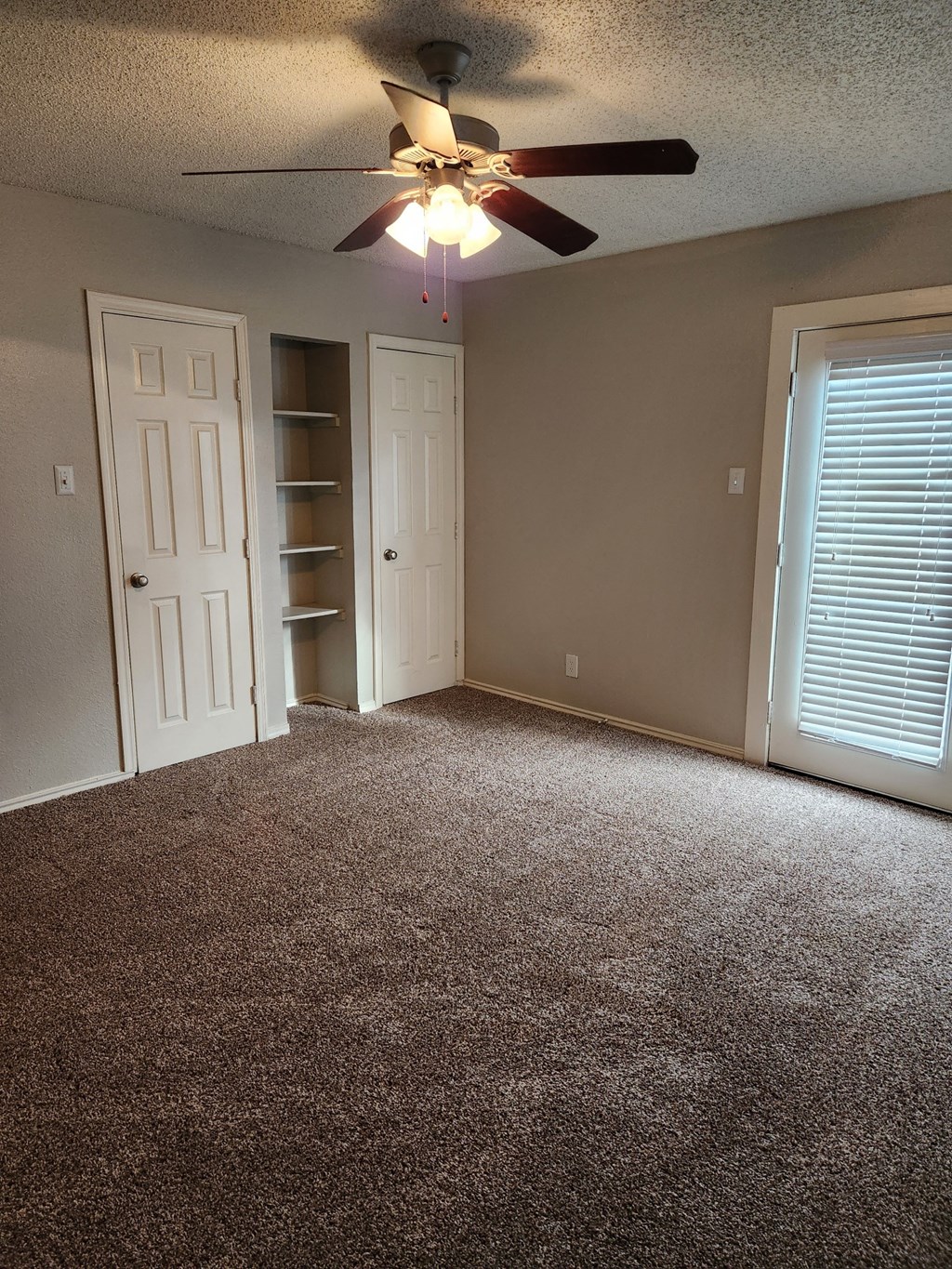 an empty room with a ceiling fan and a door to a closet