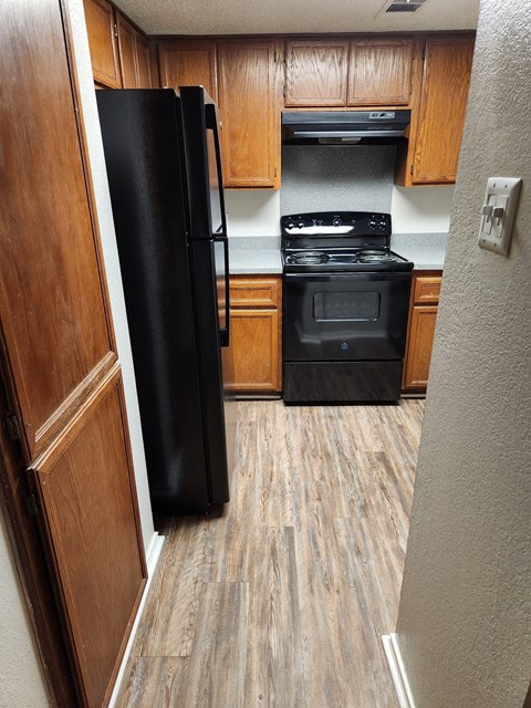 a kitchen with wood floors and a black refrigerator