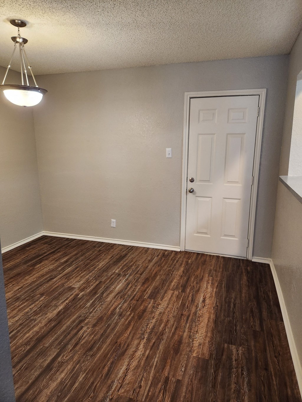 an empty room with a white door and a light hanging from the ceiling