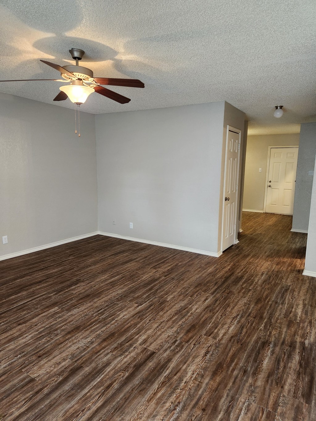 an empty living room with a ceiling fan