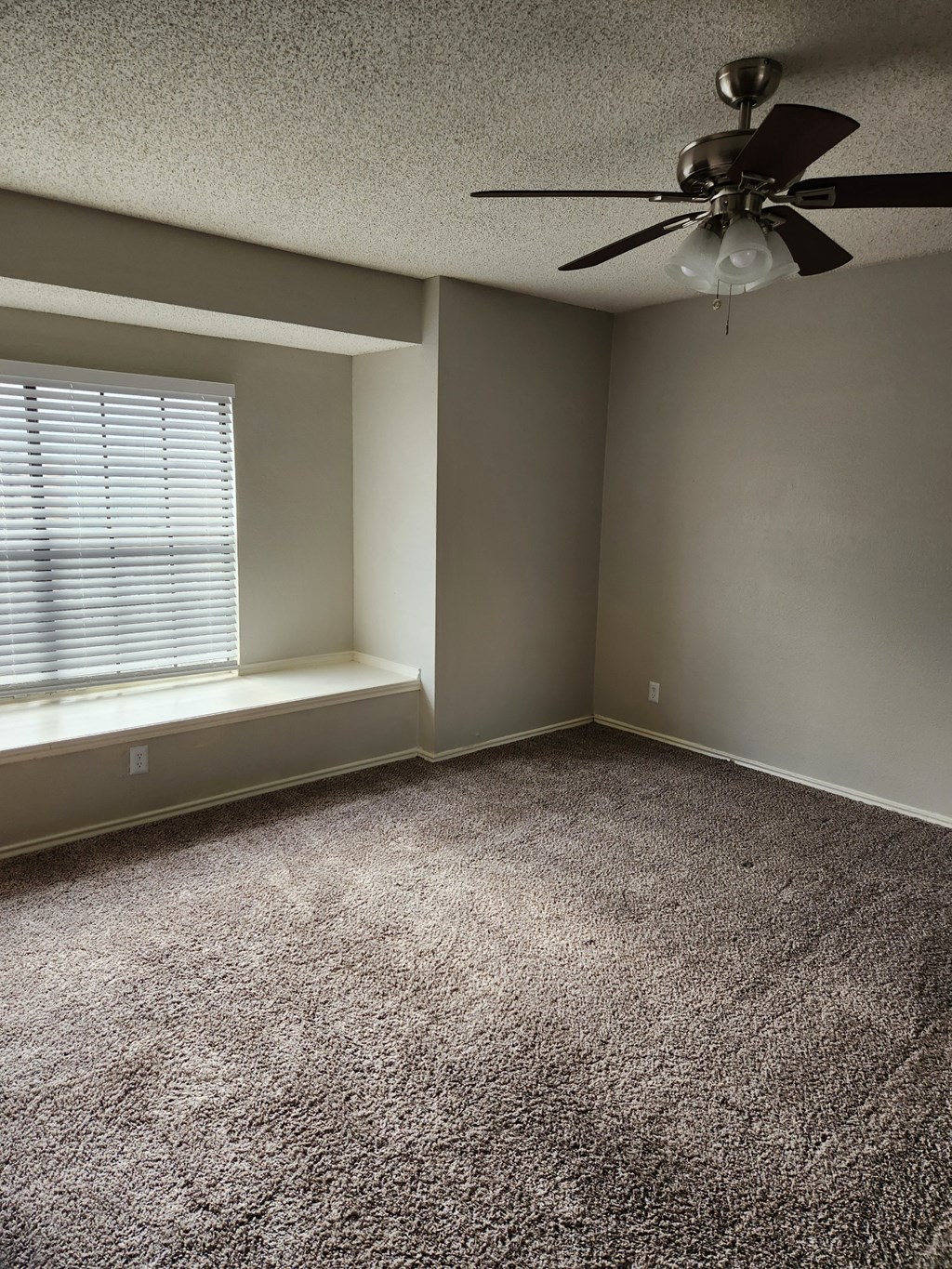 an empty room with a window and a ceiling fan
