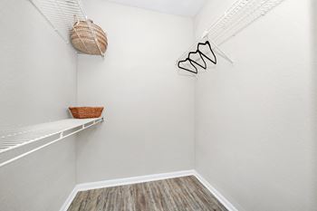 the walk in closet with a shelf and a basket on the wall