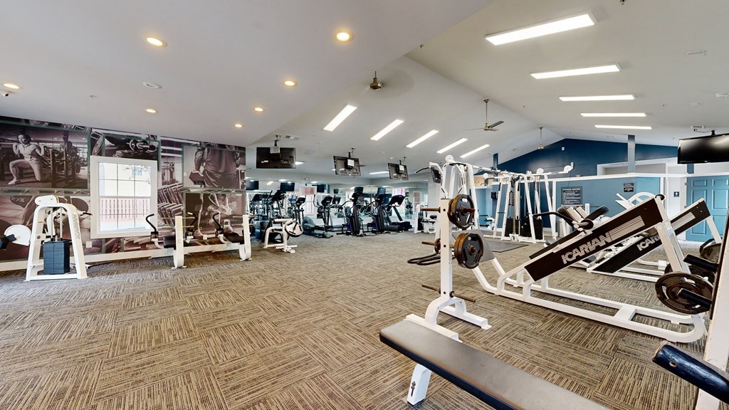 a gym with weights and cardio equipment in a building with a mural of a gym