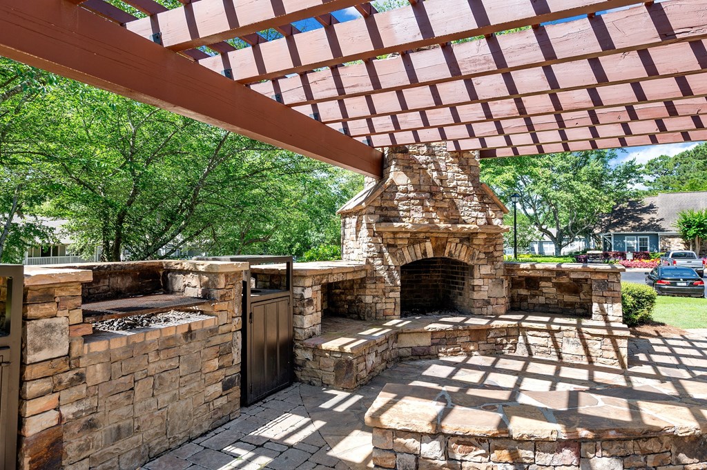 a stone outdoor fireplace with a pergola on top of it
