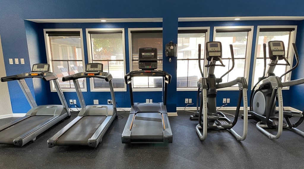 a gym with cardio equipment and windows in a building