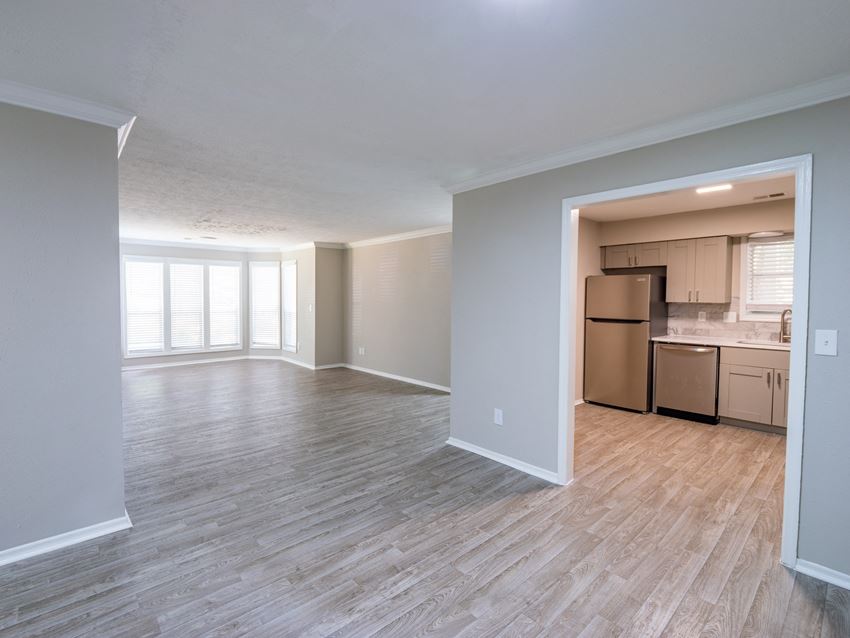 Manchester at Mansell Spacious Apartment Homes an empty living room with a kitchen in the background