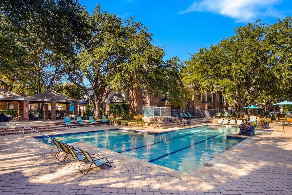 a swimming pool with chairs and trees around it