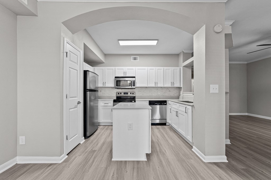 the spacious kitchen with white cabinets and stainless steel appliances