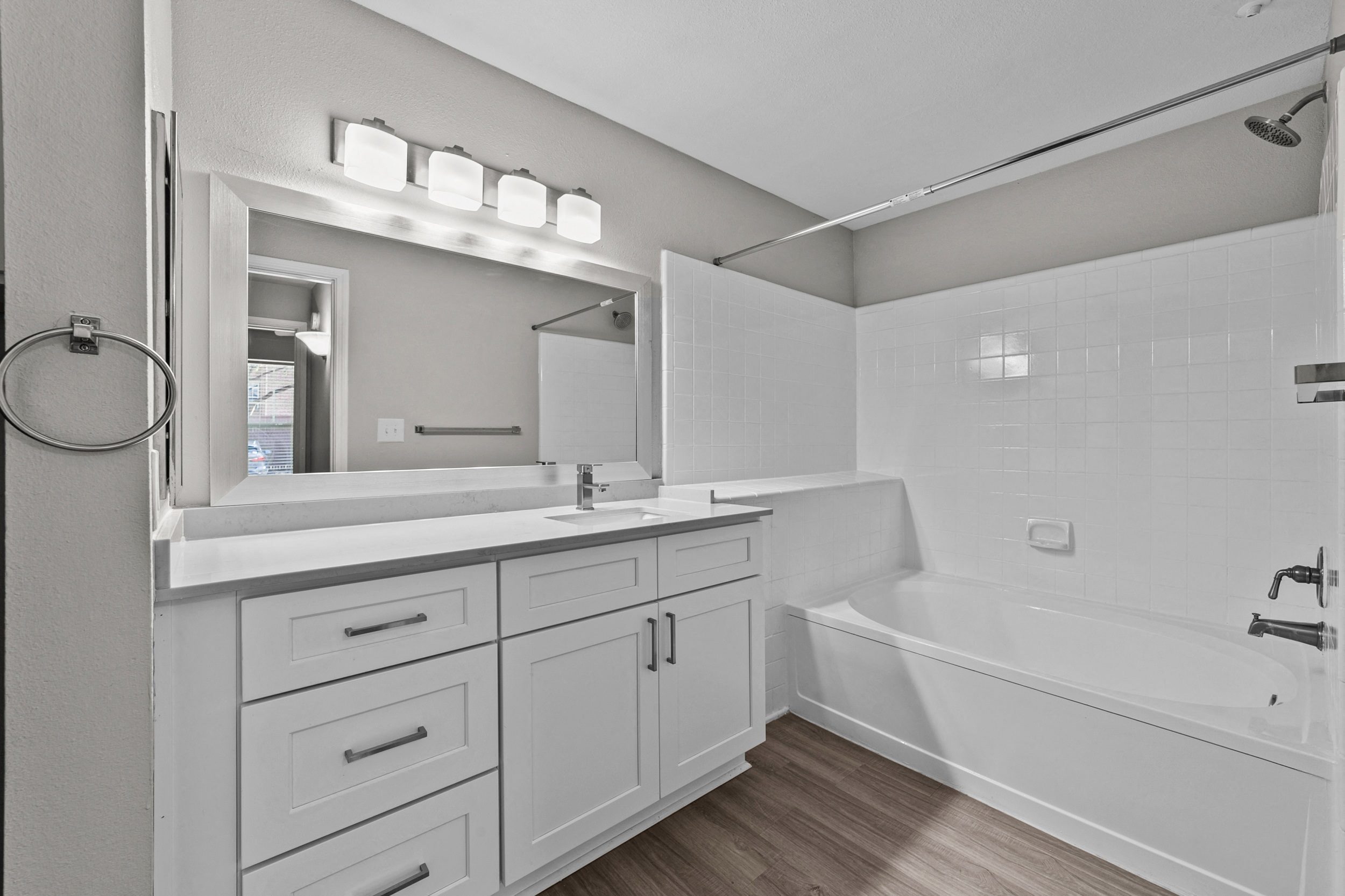a white bathroom with a tub and a sink and a mirror