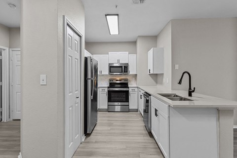 an empty kitchen with white cabinets and stainless steel appliances